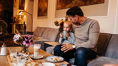 Vater und Sohn sitzen mit Kuchen und Kaffee in der gemütlichen Lounge des Familienhotels Landhaus Averbeck in der Lüneburger Heide.