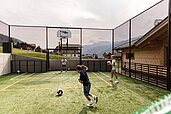 Ein paar Kinder spielen Fussball im Funcourt im Almfamilyhotel Scherer in Tirol.