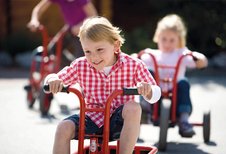 Glückliche Kinder fahren auf dem Dreirad auf dem Außengelände des Familienhotels Sonnenpark.