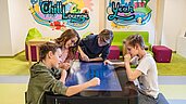 Einige Teenager spielen ein digitales Tischspiel im Familienhotel Zauchenseehof im Salzburger Land