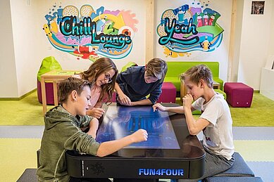 Einige Teenager spielen ein digitales Tischspiel im Familienhotel Zauchenseehof im Salzburger Land