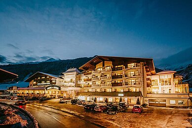 Außenansicht des Familienhotels Alpenhotel Kind in Tirol bei Nacht. Das Hotel ist schön beleuchtet und liegt direkt am familienfreundlichen Skigebiet. 