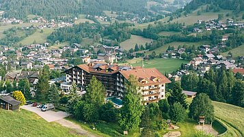 Aufnahme des Familienhotels Kirchheimerhof in Kärnten mit einer großen Grünfläche rund um das Hotel.