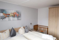 Ein Doppelzimmer mit Kinderbett im Familienhotel Monikas Ferienhof Sauerland.