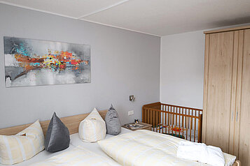 Ein Doppelzimmer mit Kinderbett im Familienhotel Monikas Ferienhof Sauerland.