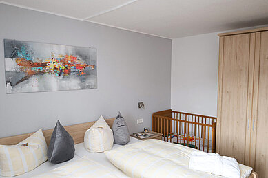 Ein Doppelzimmer mit Kinderbett im Familienhotel Monikas Ferienhof Sauerland.