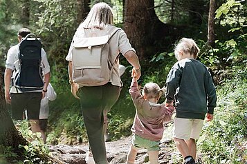 Familie wandert durch den Wald im Familienurlaub in Tirol