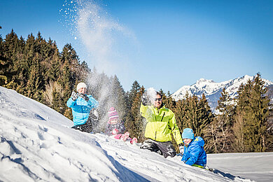 Familie tobt im Schnee.