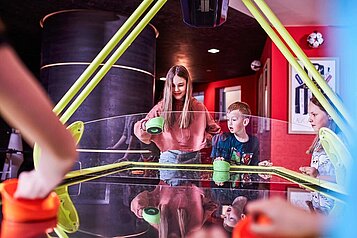 Einige Kinder spielen Airhockey im Teenclub im Familienhotel Aigo Welcome family in Oberösterreich