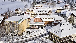 Das Familienhotel Engel im Schwarzwald umgeben von verschneiter Landschaft.