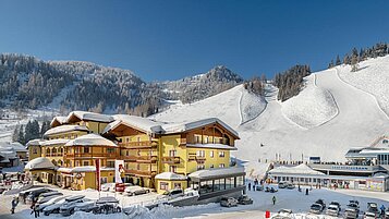 Blick auf das verschneiten Familienhotel Zauchenseehof mit den Skipisten im Hintergrund