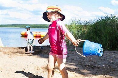 Mädchen spielt mit dem Sand am hoteleigenen Seestrand des Familienhotels Borchard's Rookhus.