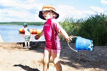 Mädchen spielt mit dem Sand am hoteleigenen Seestrand des Familienhotels Borchard's Rookhus.