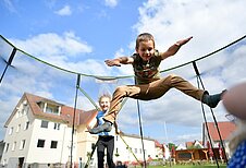 Junge spielt mit dem Fußball auf dem Außenspielplatz des Familienhotels Rhön Feeling. Auf dem Spielplatz gibt es außerdem eine blaue Rutsche, Kletternetze und Schaukeln.