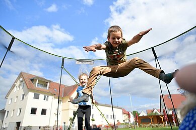 Junge spielt mit dem Fußball auf dem Außenspielplatz des Familienhotels Rhön Feeling. Auf dem Spielplatz gibt es außerdem eine blaue Rutsche, Kletternetze und Schaukeln.