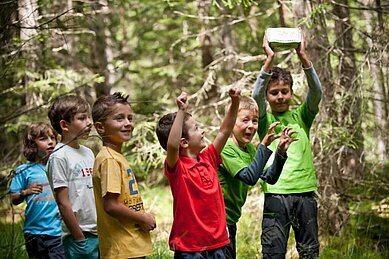 Kinder des Familienhotels Engel Gourmet & Spa sind auf einem Ausflug mit dem Happy-Club im Wald in Südtirol.