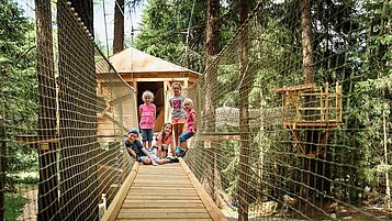 Kinder spielen auf dem Baumhausweg des Familienhotels Alpenhotel Kindl in Tirol.