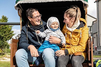 Familie mit Kleinkind genießt die herbstliche Sonne in einem Strandkorb im Familienurlaub an der Nordsee