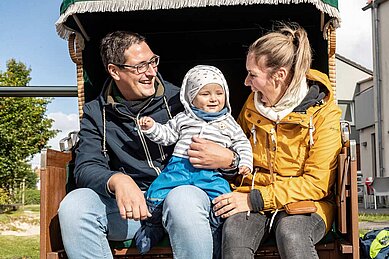 Familie mit Kleinkind genießt die herbstliche Sonne in einem Strandkorb im Familienurlaub an der Nordsee