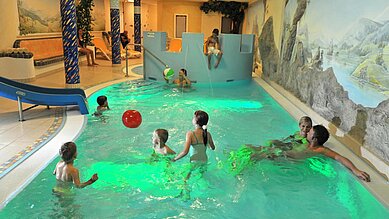 Ein paar Kinder spielen mit einem Ball im Indoorpool im Familienhotel Zauchenseehof im Salzburger Land