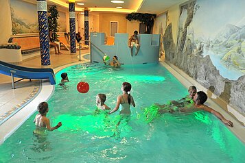 Ein paar Kinder spielen mit einem Ball im Indoorpool im Familienhotel Zauchenseehof im Salzburger Land