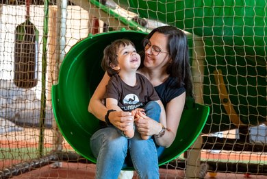Mutter und Kind haben Spaß auf der Rutsche im Indoor-Spielbereich des Familienhotels Petschnighof in Kärnten.