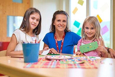 Kinder gemeinsam mit einer Kinderbetreuerin beim Basteln im Familienhotel Schreinerhof im Bayerischen Wald.