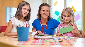 Kinder gemeinsam mit einer Kinderbetreuerin beim Basteln im Familienhotel Schreinerhof im Bayerischen Wald.