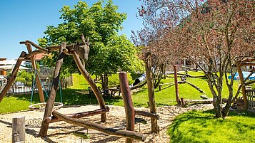 Klettermöglichkeiten aus Baumstämmen und viel Grünfläche auf dem Außenspielplatz im Familienhotel Spa- & Familien-Resort Krone im Allgäu.