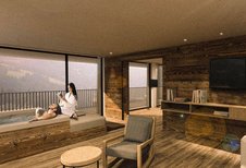 Paar entspannt am privaten Whirlpool mit Bergblick, umgeben von modernen Holzmöbeln in gemütlicher Atmosphäre im Alpura Retreat.