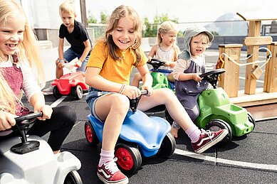 Kinder fahren auf der Bobbycar-Rennstrecke des Familienhotels Allgäuer Berghof.