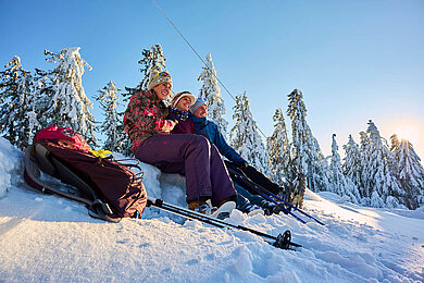 Eine Gruppe Winterwanderer macht eine Pause in der Nähe von Sankt Englmar im Bayerischen Wald im Schnee.