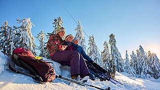 Eine Gruppe Winterwanderer macht eine Pause in der Nähe von Sankt Englmar im Bayerischen Wald im Schnee.